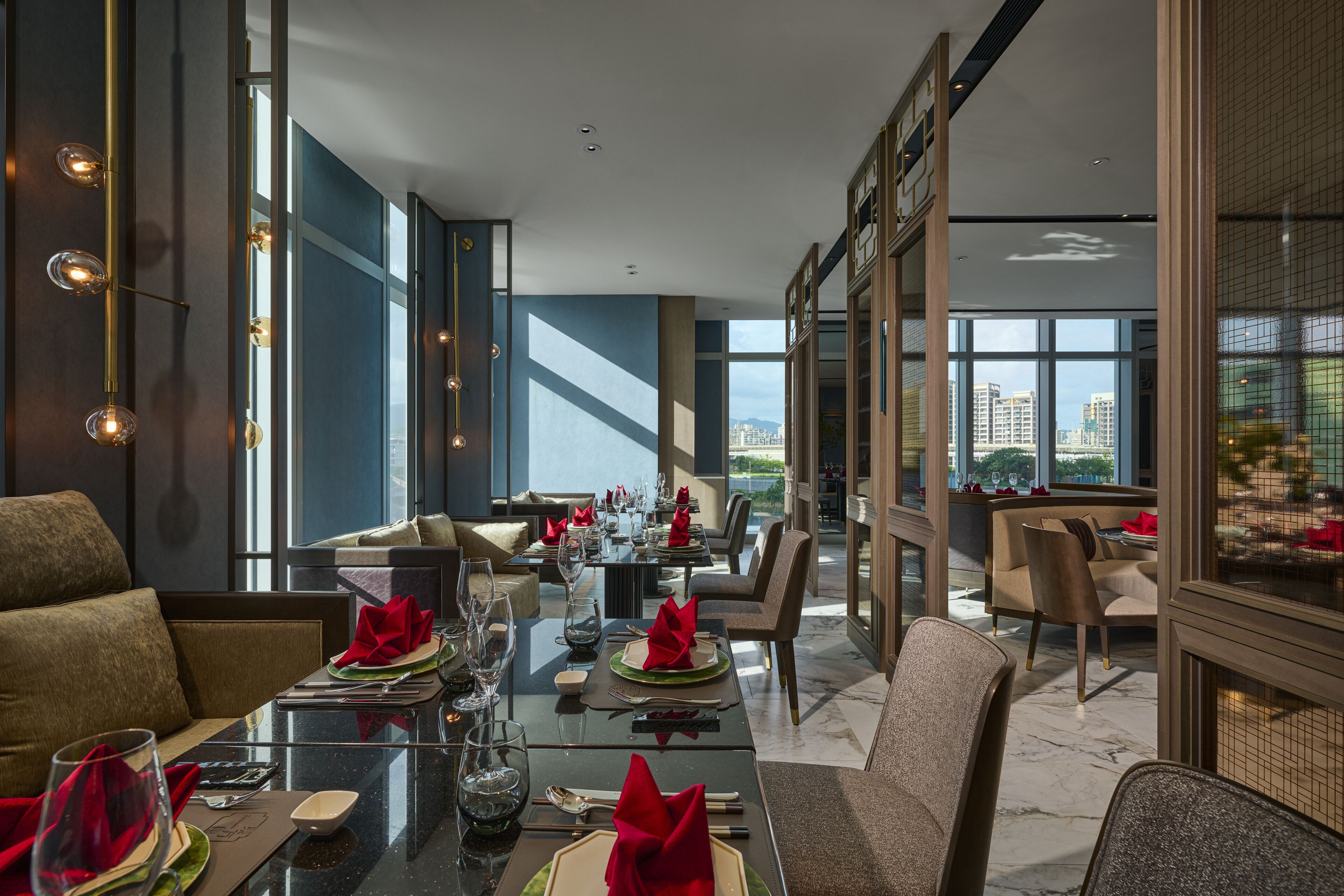 A modern dining area with tables set for a meal, large windows, and a view of the cityscape.