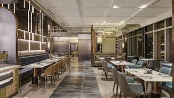 Un restaurant moderne doté de longues tables conviviales, de banquettes et d’un bar central.