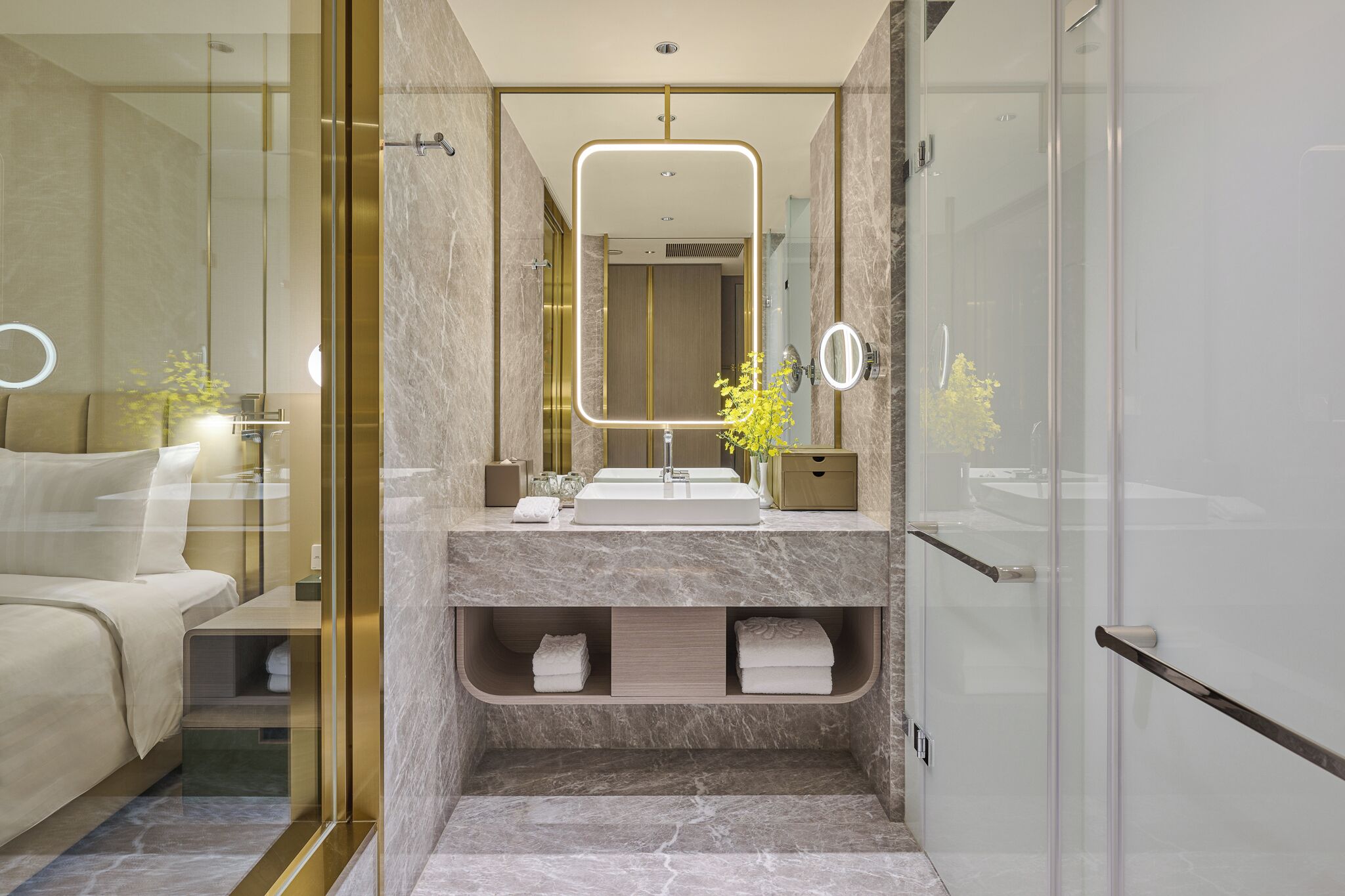 A modern bathroom with a glass shower enclosure, a marble vanity, and a large mirror.