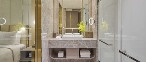 A modern bathroom with a glass shower enclosure, a marble vanity, and a large mirror.