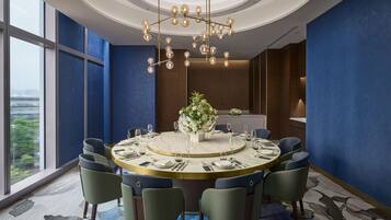 A modern dining area with a round table, chairs, and a chandelier.