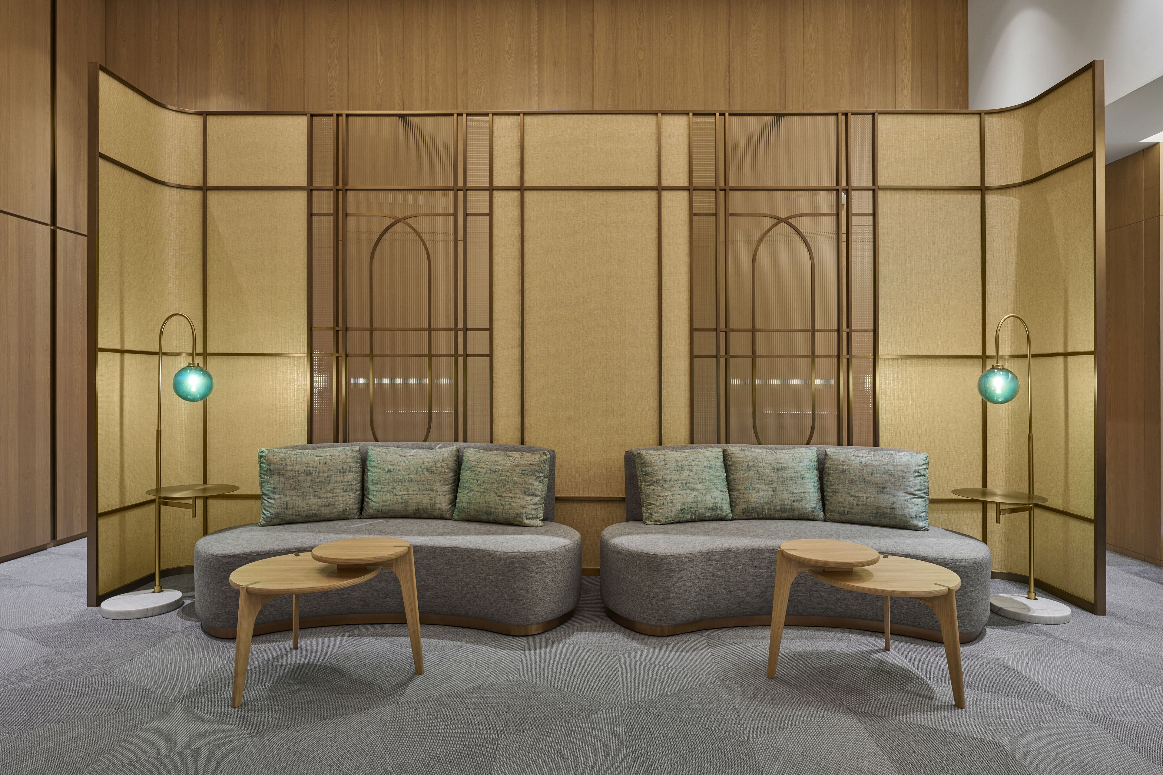 Een moderne kamer met een hoekbank, twee bijzettafeltjes en een decoratieve scheidingswand met verticale lijnen.