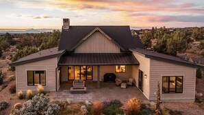 A modern house with a large patio, a fireplace, and a view of the surrounding landscape. - Brasada Ranch | High Desert Modern Luxury | Sauna (Powell Butte)