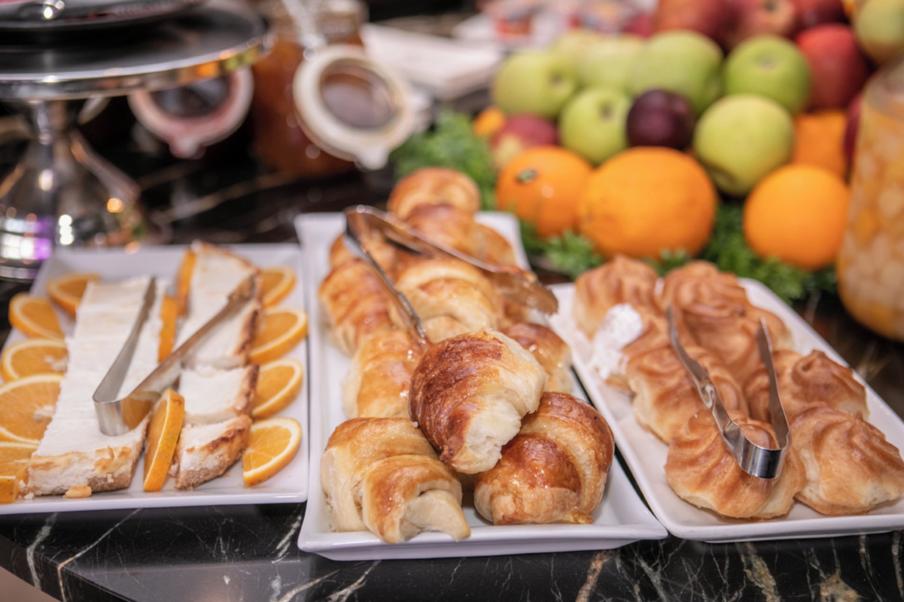 A buffet with pastries, fruits, and a coffee station.