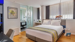 A modern hotel room with a large bed, a desk, and a bathroom visible through a glass door. - Ultra Ben Yehuda (Tel Aviv)