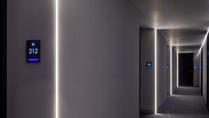 A modern hallway with illuminated floor numbers and a sleek, metallic wall design. - Ultra Ben Yehuda (Tel Aviv)