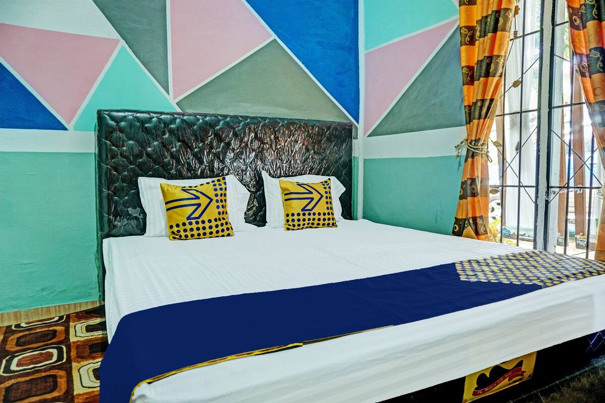 A bed with a blue and white bedspread, two pillows with yellow and black patterns, and a textured headboard.