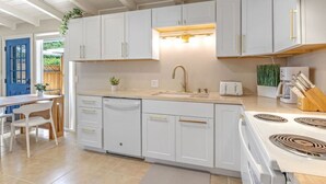 Una cucina moderna con mobili bianchi, forno integrato e lavandino.