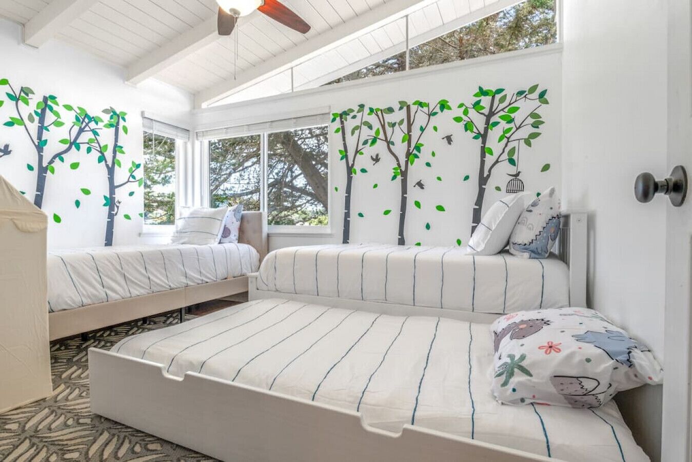 Ein Schlafzimmer mit zwei Betten, einem großen Fenster und einem Deckenventilator.