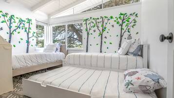 Ein Schlafzimmer mit zwei Betten, einem großen Fenster und einem Deckenventilator.