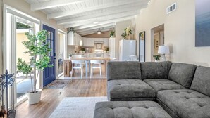 Un'ampia zona giorno con un divano a tre posti color grigio, un tavolo da pranzo con sedie e una cucina sullo sfondo.