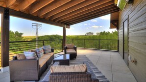 A covered outdoor seating area with wicker furniture and a view of the countryside.