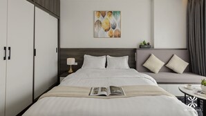A modern hotel room with a large bed, a sofa, a small table with a plant, and a painting on the wall. - NB APARTMENT - KIM MA (Hanoi)