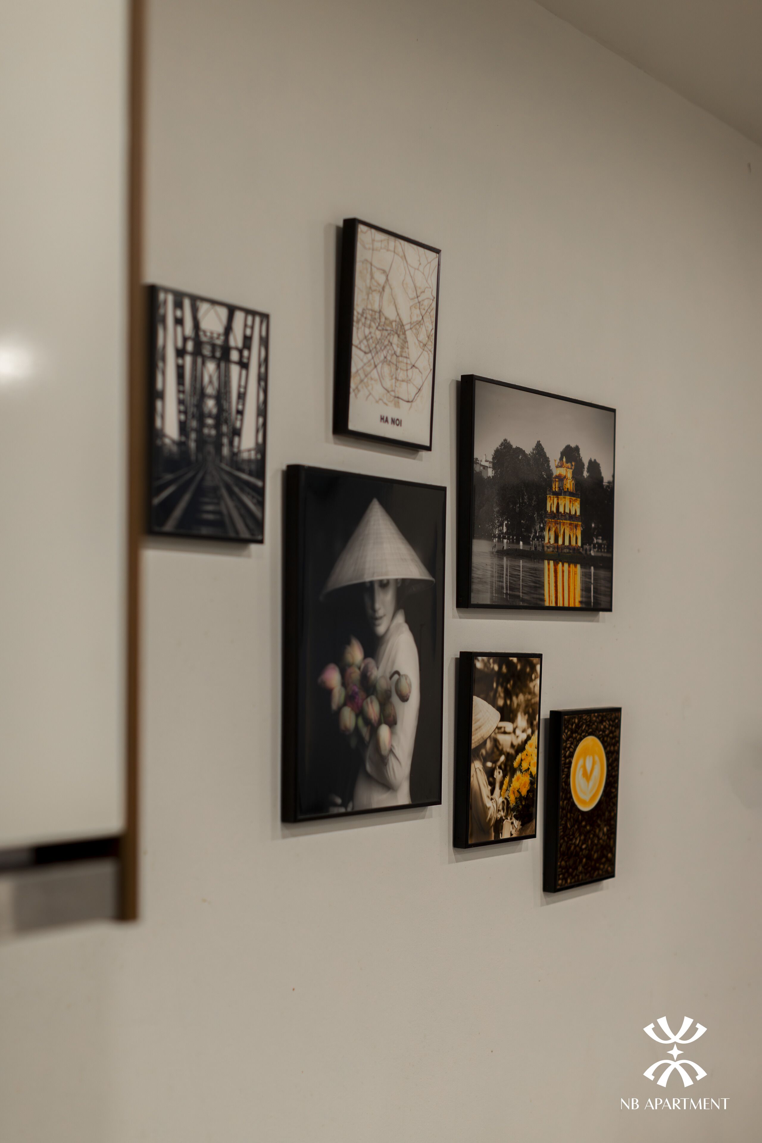 A wall with various framed artworks, including a bridge, a person with a conical hat, and a building by water.