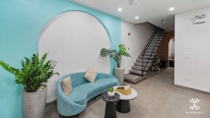 A modern living room with a teal sofa, a coffee table, and potted plants. - NB APARTMENT - KIM MA (Hanoi)