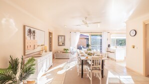 Un comedor luminoso e soleado con una mesa larga, sillas y un ventilador de techo.
