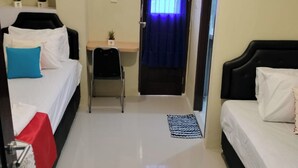Een hotelkamer met twee bedden, een bureau, een stoel, een airconditioner en een raam met gordijnen.