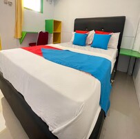 A bed with a white and blue bedspread, a black headboard, and two pillows with red and blue accents.