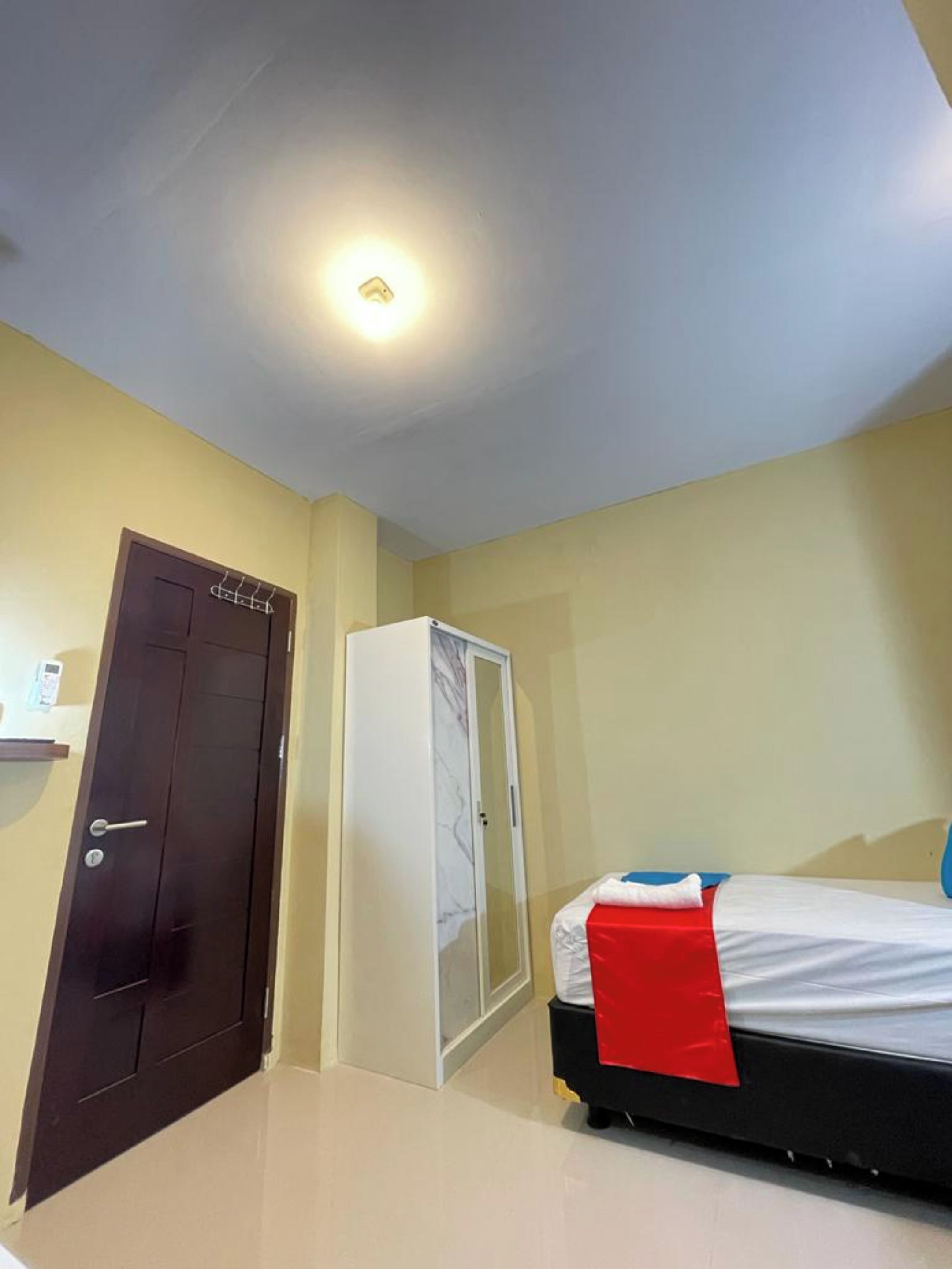 Un dormitorio con cama, armario, puerta y lámpara.