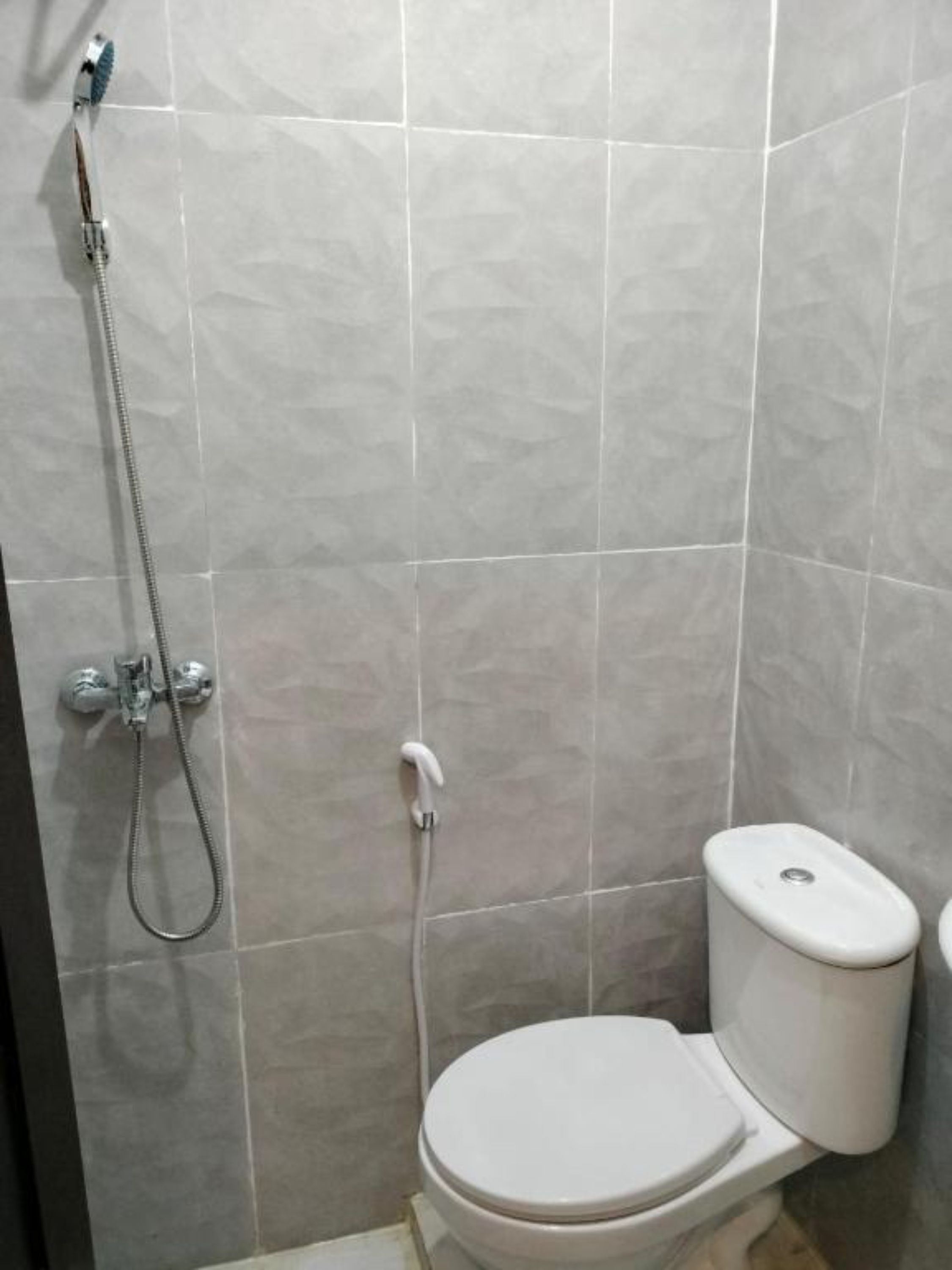 A bathroom with a toilet, a shower, and tiled walls.