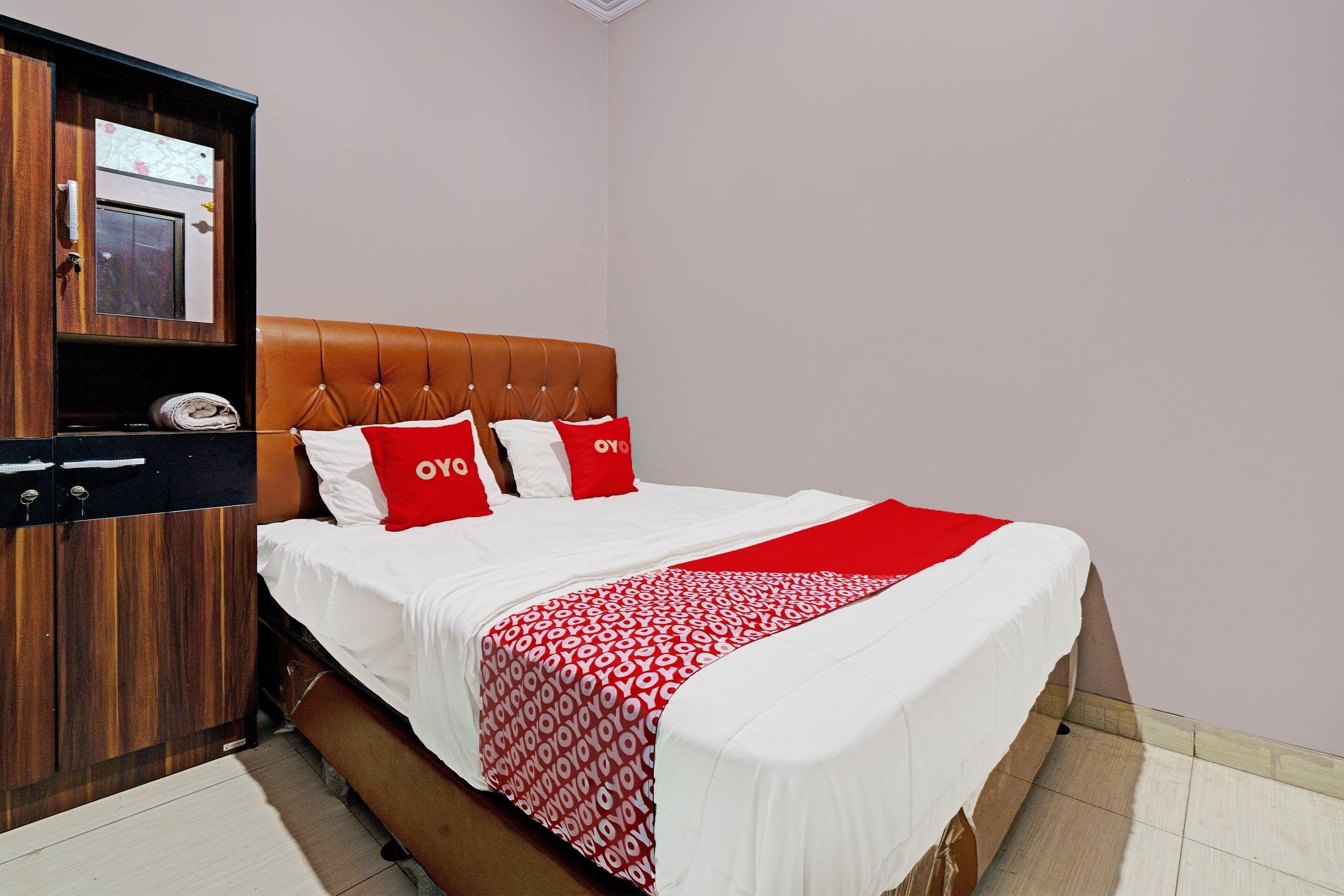 Una habitación de hotel con una cama, un armario de madera y un espejo.