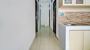 Un pasillo estrecho con una zona de cocina a la derecha, que incluye un lavamanos y armarios.