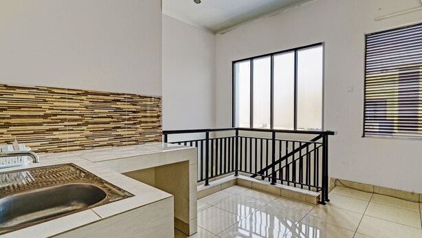 Una cocina moderna con un lavaplatos integrado, barandilla negra y un amplio ventanal que proporciona luz natural.