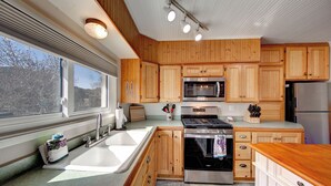 Une cuisine moderne avec des meubles en bois, des appareils électroménagers en acier inoxydable et une grande fenêtre qui laisse entrer la lumière naturelle.