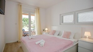A bedroom with a bed, two bedside tables, a window with blinds, and a view of the outdoors. - Luxurious home in Nin (Nin)
