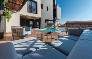 Un espace piscine extérieur moderne, aménagé avec un canapé, une table et une plante suspendue.