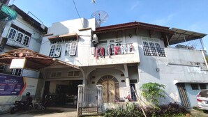 A two-story building with a balcony, a satellite dish, and a gated entrance. - Hotel O Excellent Kost (Jambi)