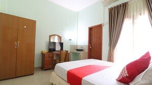 A bedroom with a bed, a desk with a chair, a television, and a wardrobe. - Hotel O Excellent Kost (Jambi)
