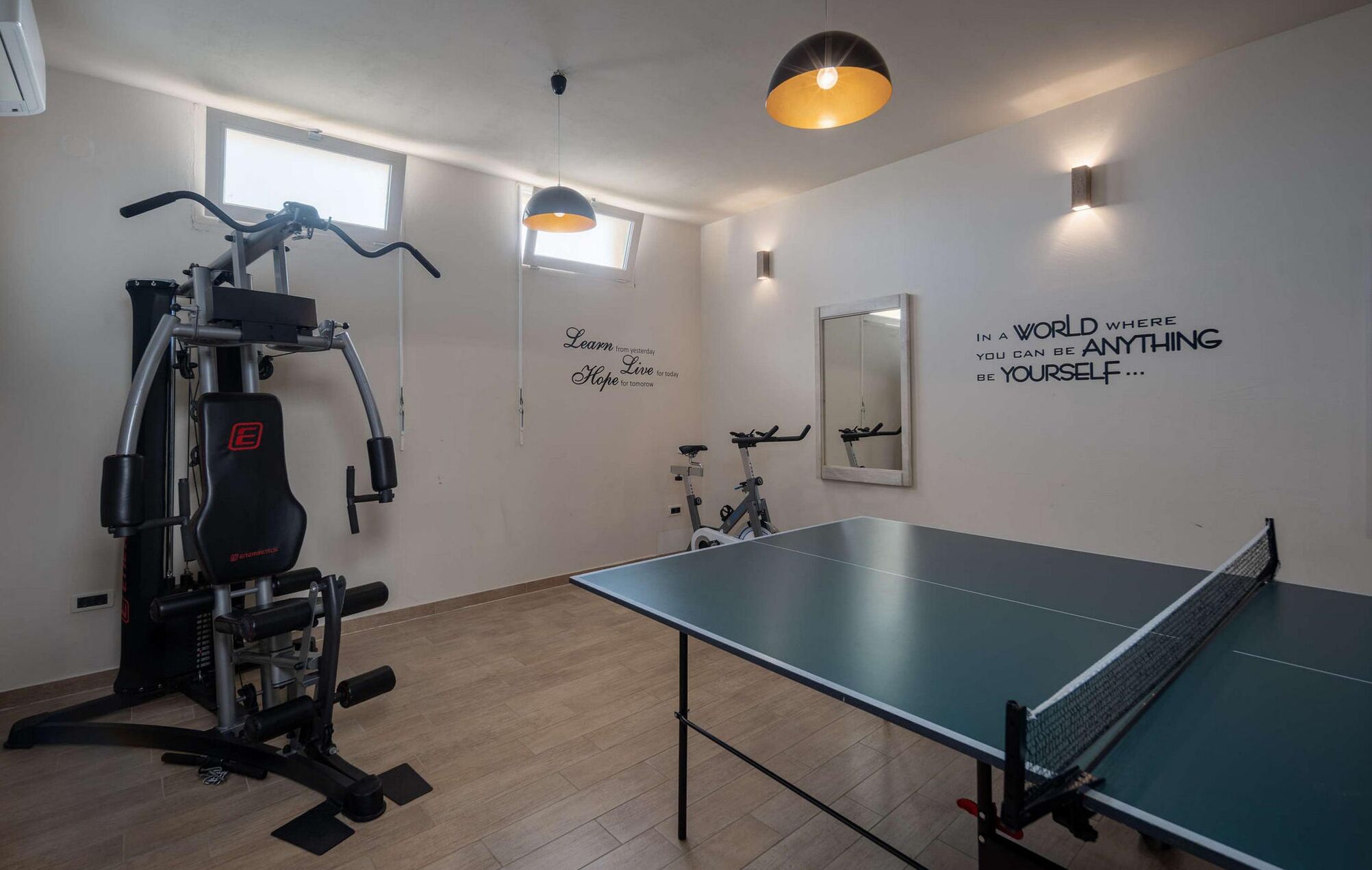 Une pièce équipée d’une table de ping-pong, de matériel d’exercice et décorée avec des œuvres d’art inspirantes.