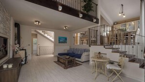 Un amplio espacio habitable con una escalera, un sofá, una mesa baja y una mesa de comedor.
