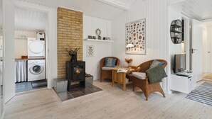 A modern living room with a fireplace, a dining area, and a kitchen with a washing machine. - Nice home in ålbæk with WiFi (Ålbæk)