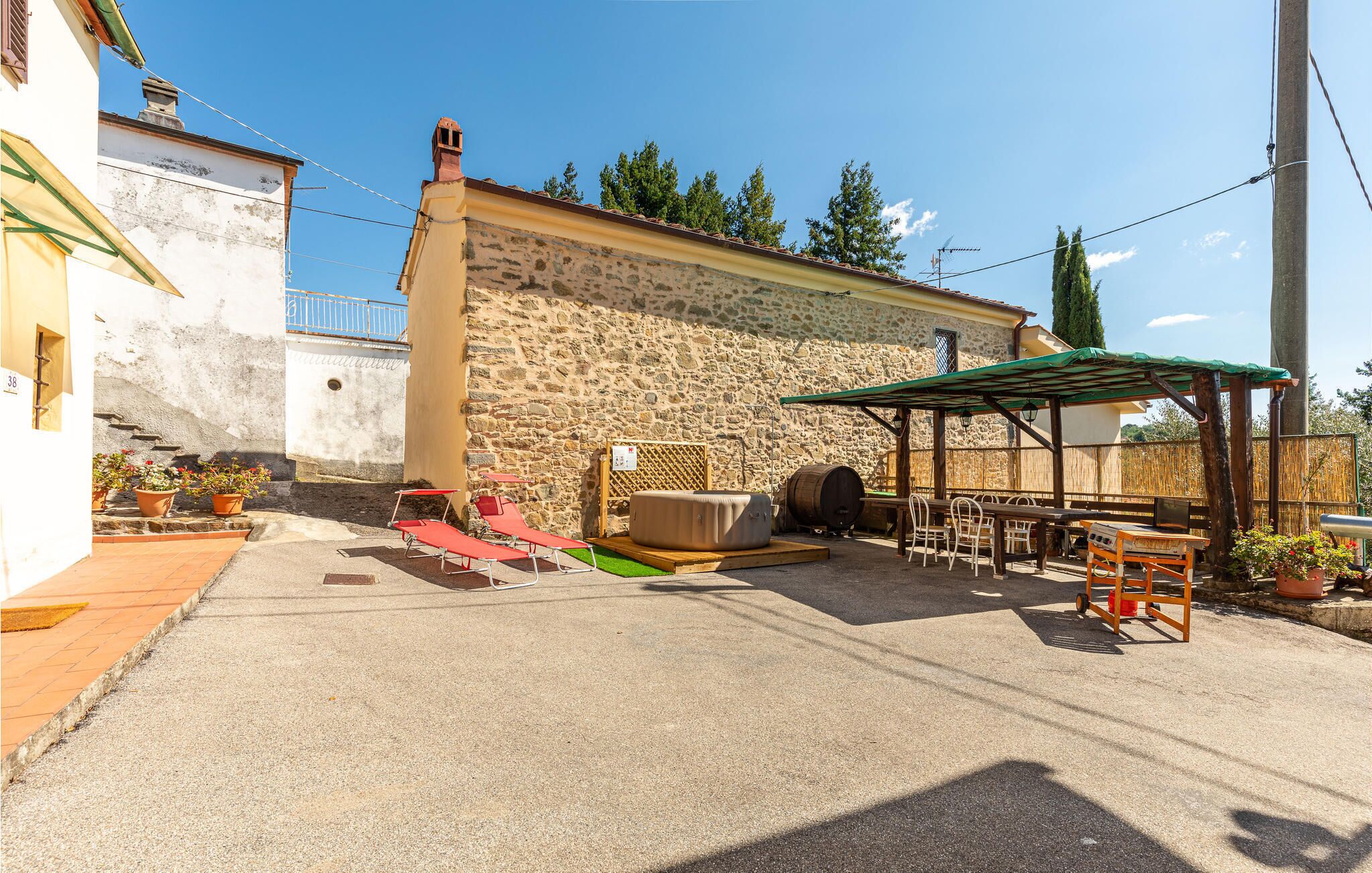A patio area with a stone wall, outdoor seating, and a barbecue grill.