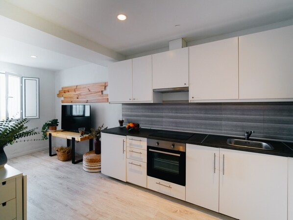 A modern kitchen with white cabinets, a black countertop, and a built-in oven.
