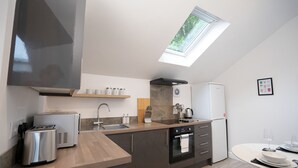 A modern kitchen with a skylight, built-in oven, and a dining area with a table and chairs.