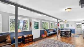 A spacious living area with a sofa, wooden chest, and dining table. - Lakeside Cabin With Private Dock & Sandy Beach (Donnelly)