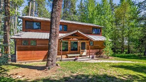 A wooden cabin with a porch, large windows, and a metal roof, surrounded by trees. - Lakeside Cabin With Private Dock & Sandy Beach (Donnelly)