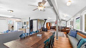 A spacious kitchen with a dining area, a living room with a sofa, and a stone wall. - Lakeside Cabin With Private Dock & Sandy Beach (Donnelly)