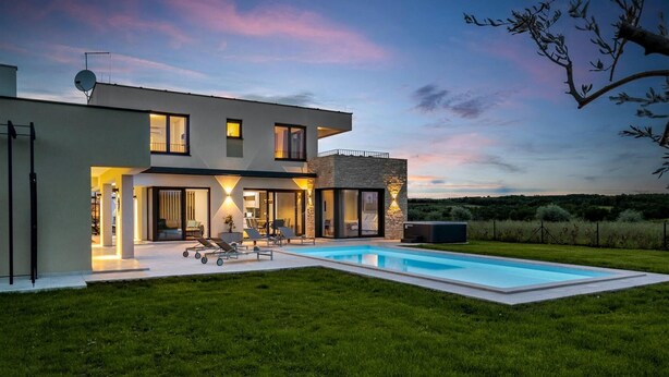 Ein modernes, zweistöckiges Haus mit Schwimmbad, großen Fenstern und einem gepflegten Rasen.
