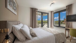 Ein Schlafzimmer mit Bett, Schreibtisch, Stuhl, Fernseher und einem Fenster mit Blick auf die Landschaft.