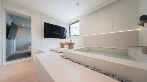 Une salle de bain moderne dotée d’une grande baignoire, d’un téléviseur à écran plat et d’une fenêtre.