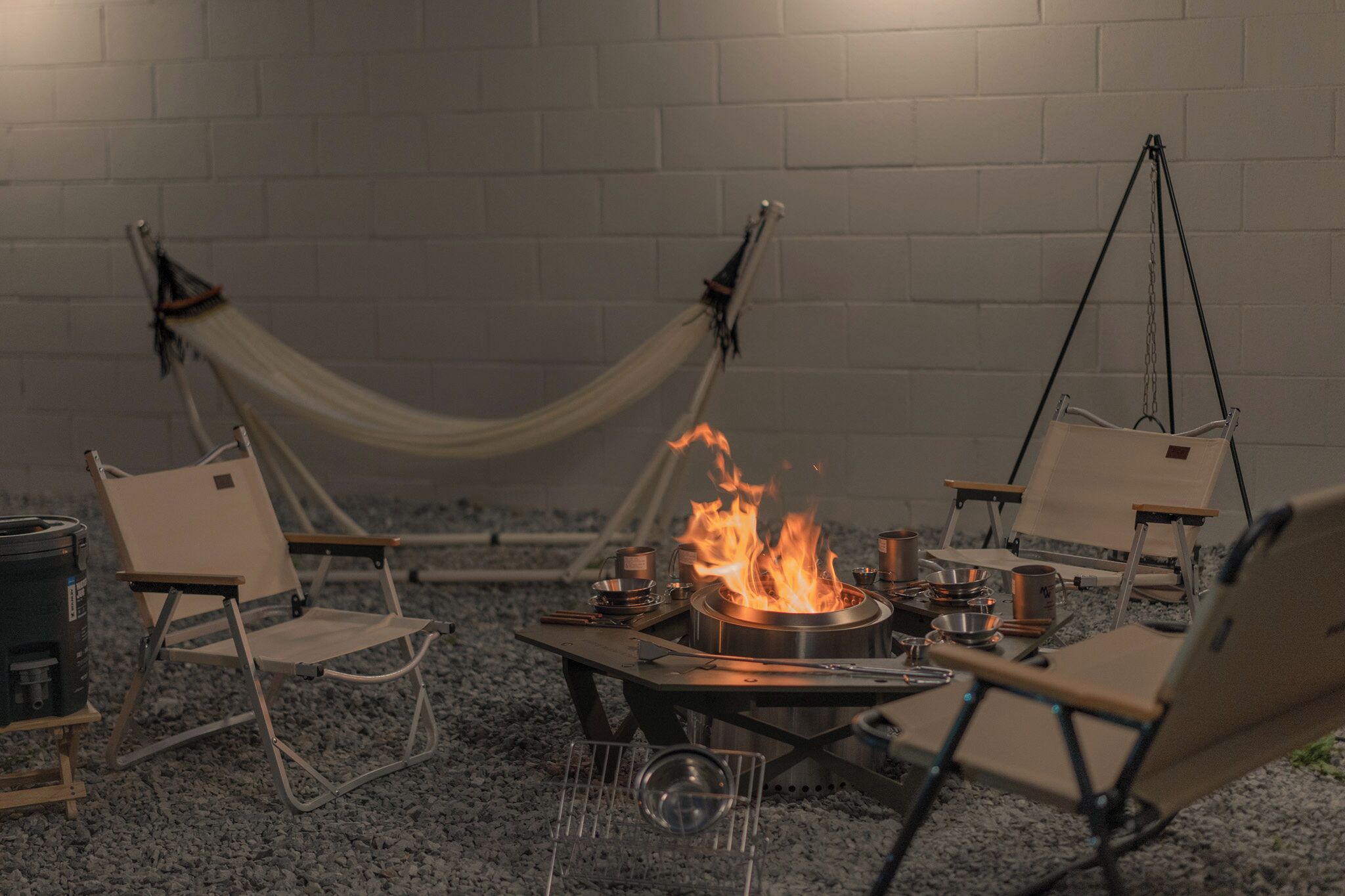 A campsite with a fire pit, camping chairs, and a hammock.