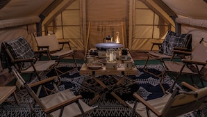 L’intérieur d’une tente accueillante, avec une table centrale, des chaises pliantes et un tapis à motifs.