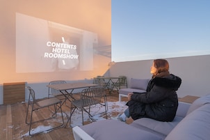 Una persona sentada en un sofá en una habitación con una pantalla de proyector mostrando