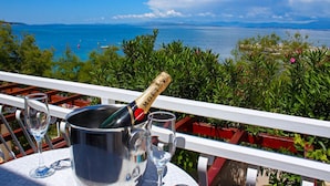 A table with a bottle of champagne, two glasses, and a metal bucket on a balcony overlooking a scenic view of the sea and mountains. - Luxurious home in Supetar (Supetar)