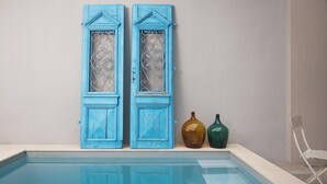 Une piscine avec deux portes bleues et deux vases décoratifs.