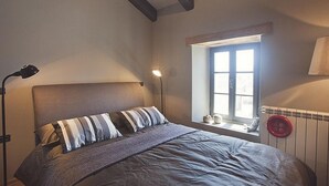 Une chambre à coucher avec un lit, une fenêtre, une lampe et un radiateur.